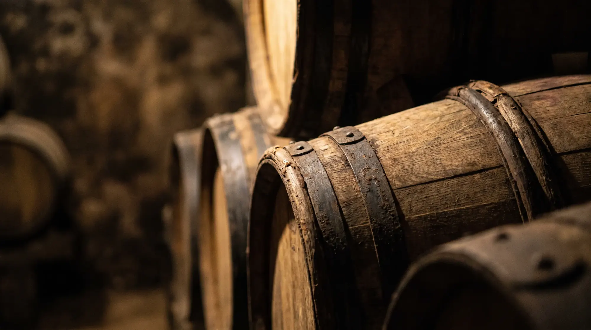 Détail de barriques de chêne empilées dans un chai, douelles et cerclage métallique