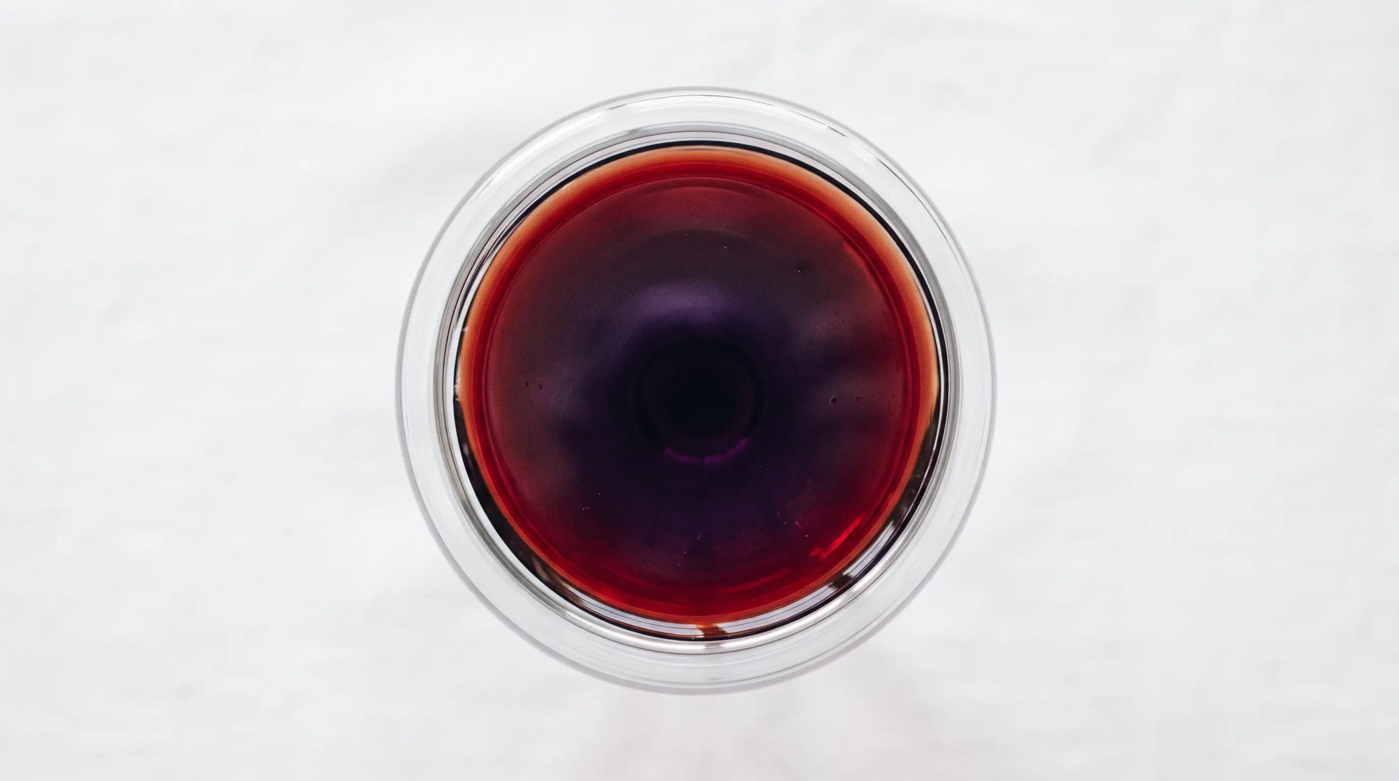Verre de vin rouge vu de dessus : disque sombre au centre, dégradé grenat sur le pourtour